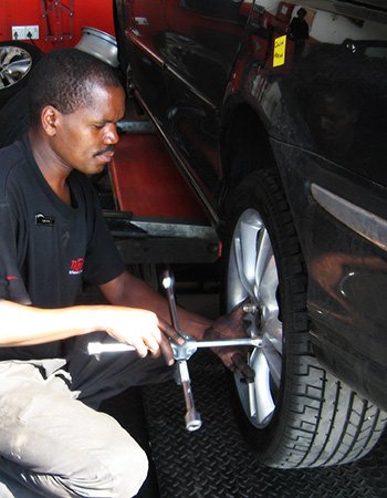 A tiger wheel & tyre technician removing the bolts from a car wheel