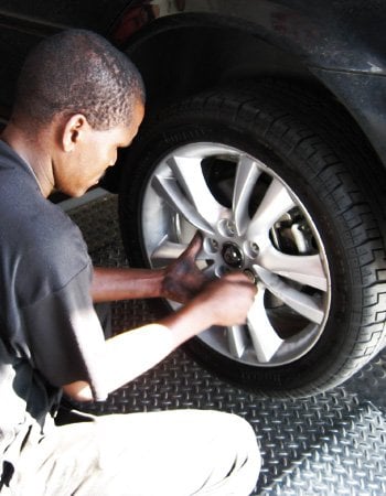 A tiger wheel & tyre technician removing the bolts from a car wheel